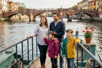 Famille avec deux enfants sur le pont d'une péniche amarrée sur la Garonne à Toulouse, avec le Pont Neuf en arrière-plan